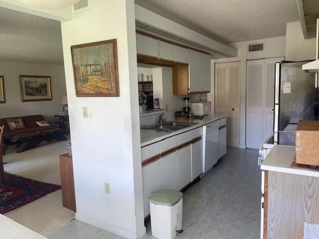 kitchen with white cabinets, white appliances, a textured ceiling, and sink