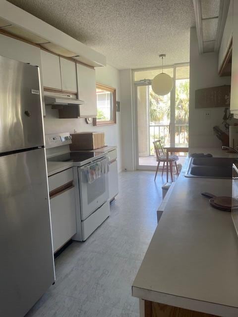 kitchen featuring white cabinets, decorative light fixtures, stainless steel refrigerator, sink, and white electric stove