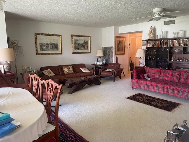 carpeted living room featuring ceiling fan and a textured ceiling