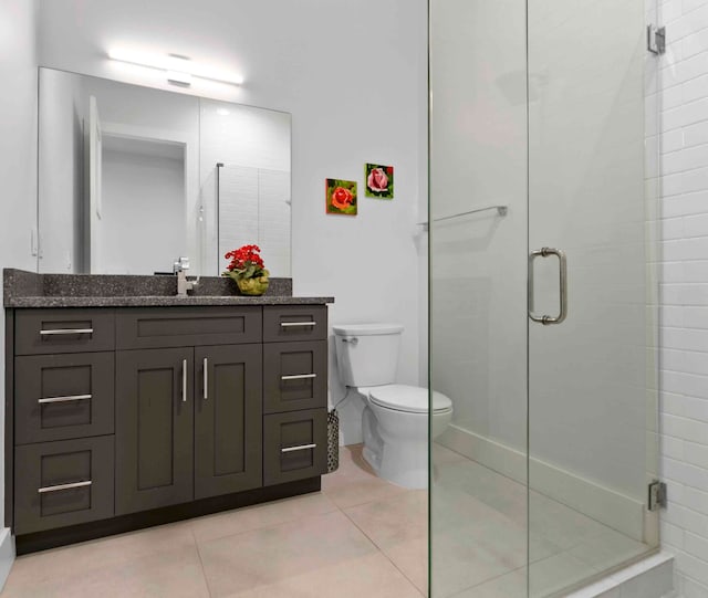 bathroom with vanity, a shower with shower door, toilet, and tile patterned flooring