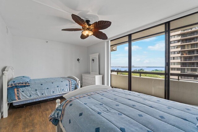 bedroom featuring access to exterior, ceiling fan, hardwood / wood-style floors, and a water view