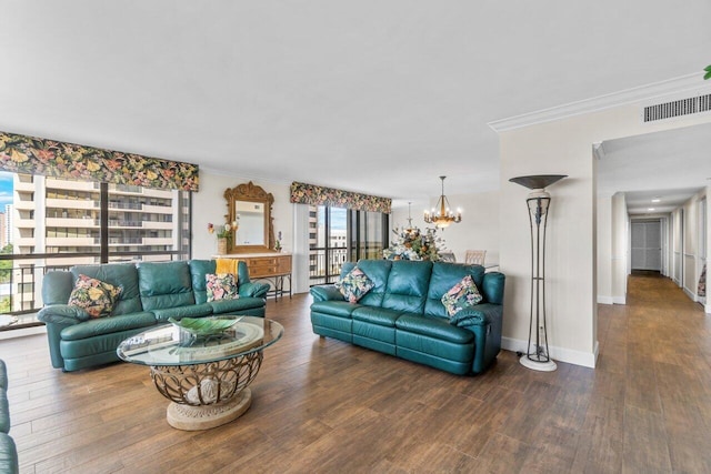 living room featuring ornamental molding, dark wood-type flooring, and an inviting chandelier