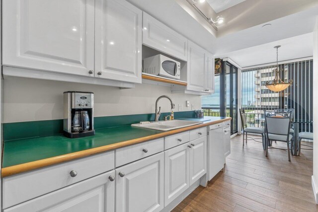 kitchen featuring white appliances, light hardwood / wood-style flooring, sink, expansive windows, and white cabinetry