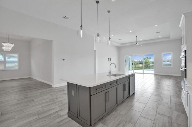 kitchen with gray cabinetry, ceiling fan with notable chandelier, sink, hanging light fixtures, and white cabinetry