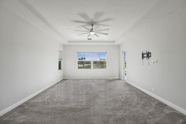 unfurnished room with carpet, a textured ceiling, a tray ceiling, and ceiling fan