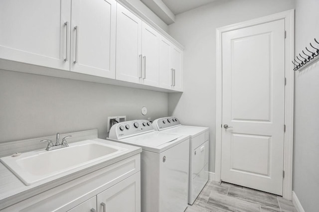 laundry area with cabinets, separate washer and dryer, and sink