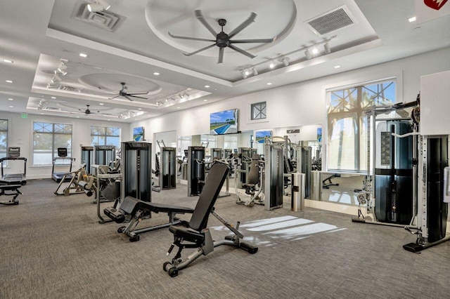 gym featuring ceiling fan and a raised ceiling