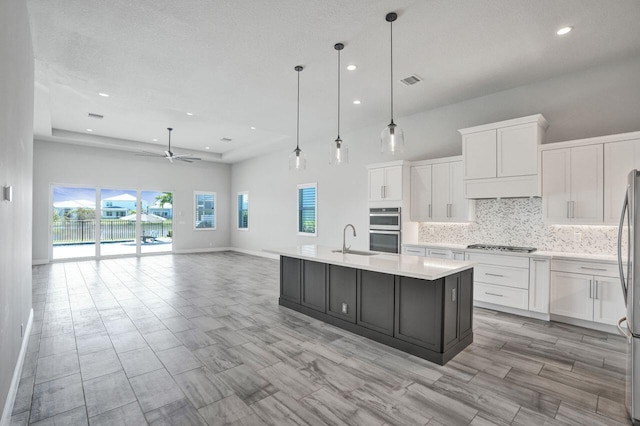 kitchen featuring pendant lighting, white cabinetry, ceiling fan, and an island with sink