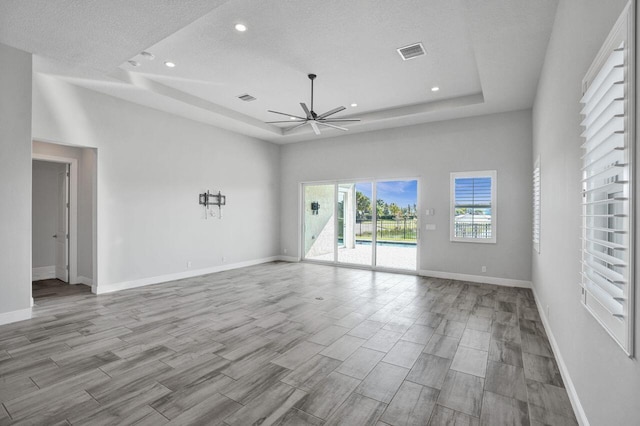 unfurnished room featuring a tray ceiling, ceiling fan, and a textured ceiling