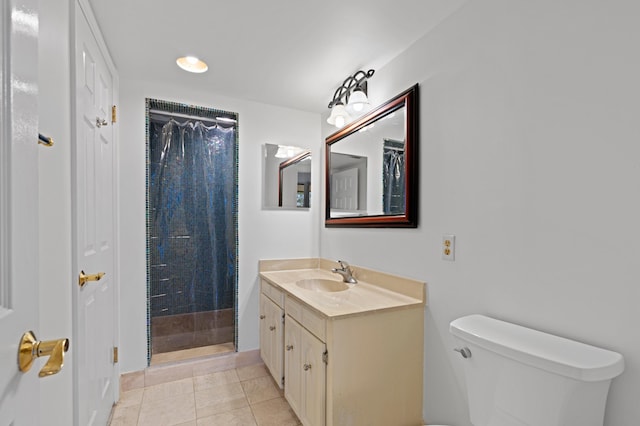 bathroom with tiled shower, tile patterned flooring, toilet, and vanity