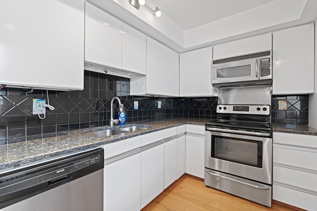 kitchen featuring stainless steel appliances, light wood-type flooring, white cabinets, and tasteful backsplash