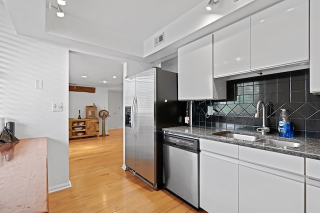 kitchen with light wood-type flooring, tasteful backsplash, sink, appliances with stainless steel finishes, and white cabinets