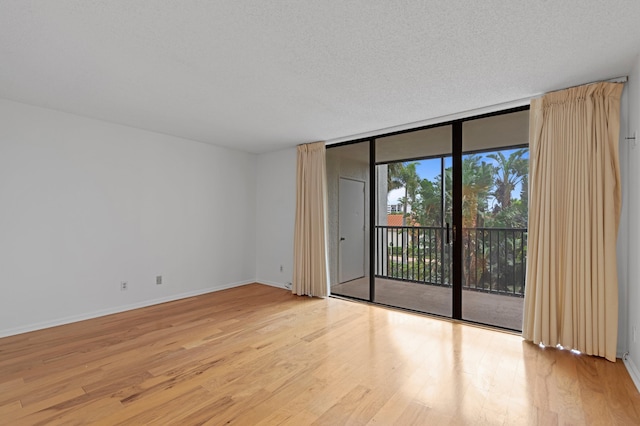 unfurnished room with floor to ceiling windows, light hardwood / wood-style floors, and a textured ceiling