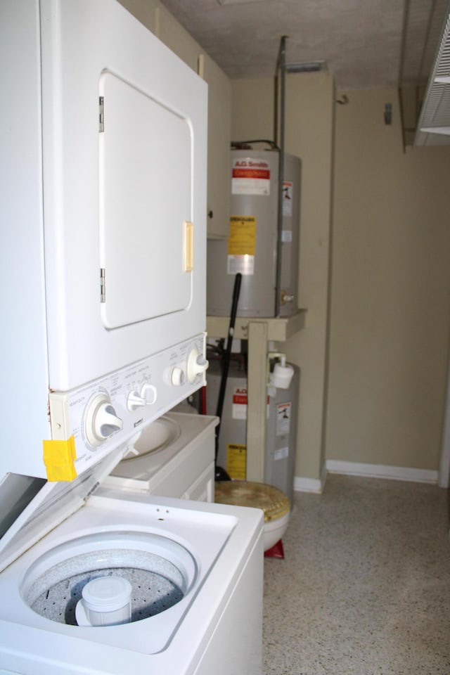 laundry room with water heater and stacked washer / dryer