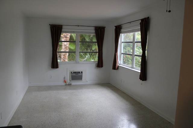 spare room featuring a wall mounted air conditioner and a wealth of natural light