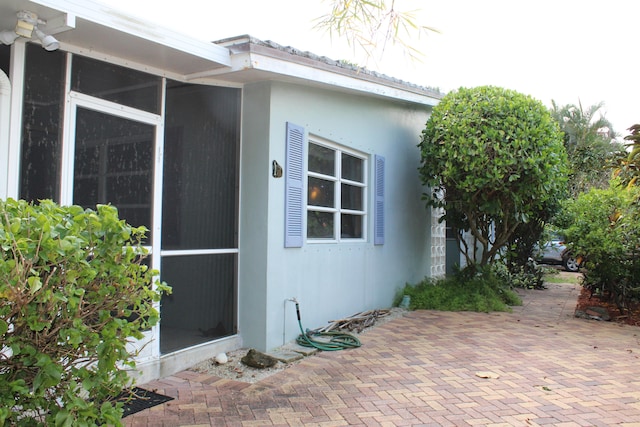 view of side of property featuring a sunroom and a patio