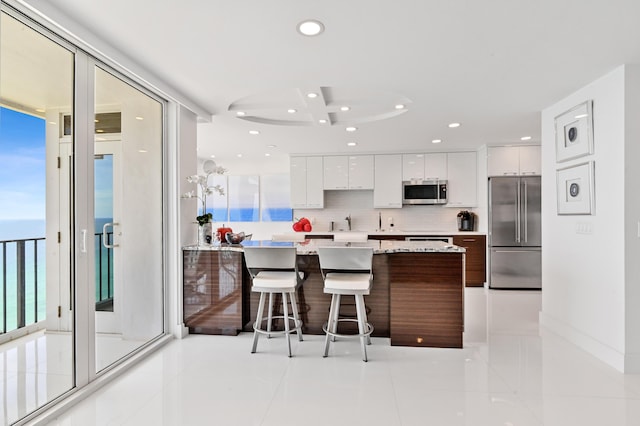 kitchen with a center island, stainless steel appliances, white cabinets, a breakfast bar area, and decorative backsplash