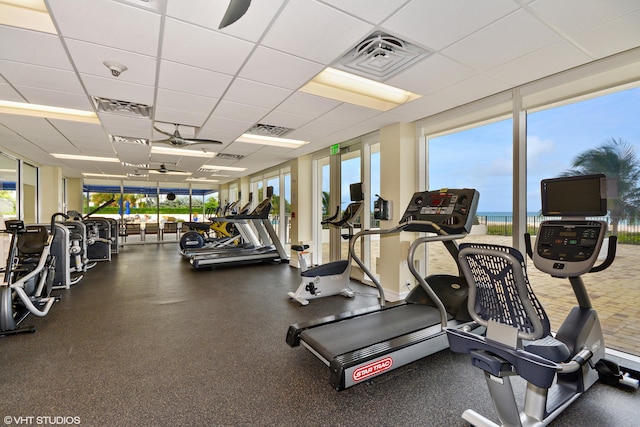 workout area with a wall of windows and a drop ceiling