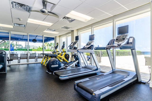 workout area featuring a paneled ceiling and expansive windows