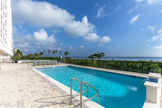 view of pool with a patio area, a water view, and pool water feature