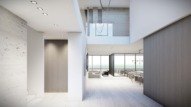 hallway with floor to ceiling windows, a high ceiling, and wood finished floors