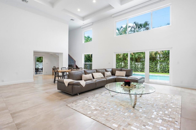 living room featuring a high ceiling, coffered ceiling, and plenty of natural light