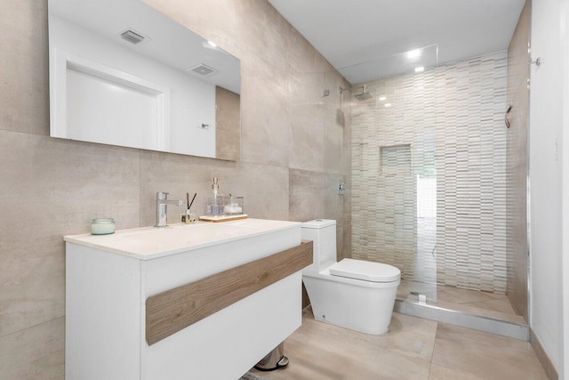 bathroom featuring vanity, a tile shower, tile walls, toilet, and tile patterned floors