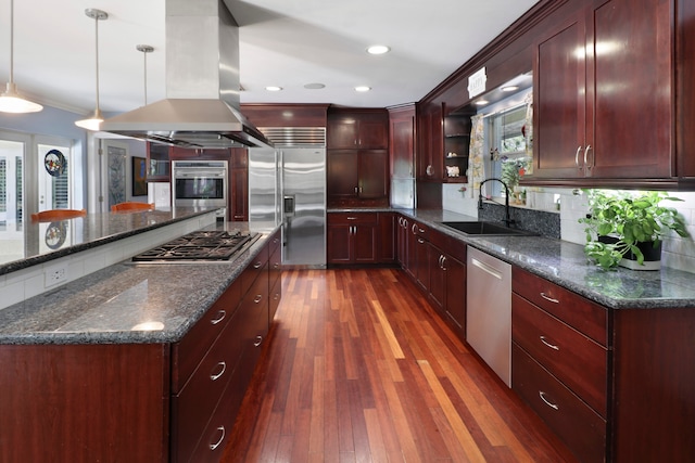 kitchen with dark hardwood / wood-style floors, dark stone countertops, sink, appliances with stainless steel finishes, and decorative light fixtures