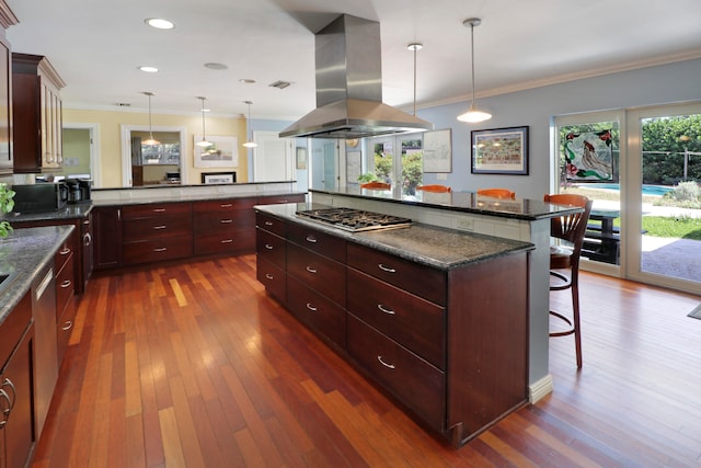 kitchen featuring island exhaust hood, stainless steel gas cooktop, decorative light fixtures, and a breakfast bar