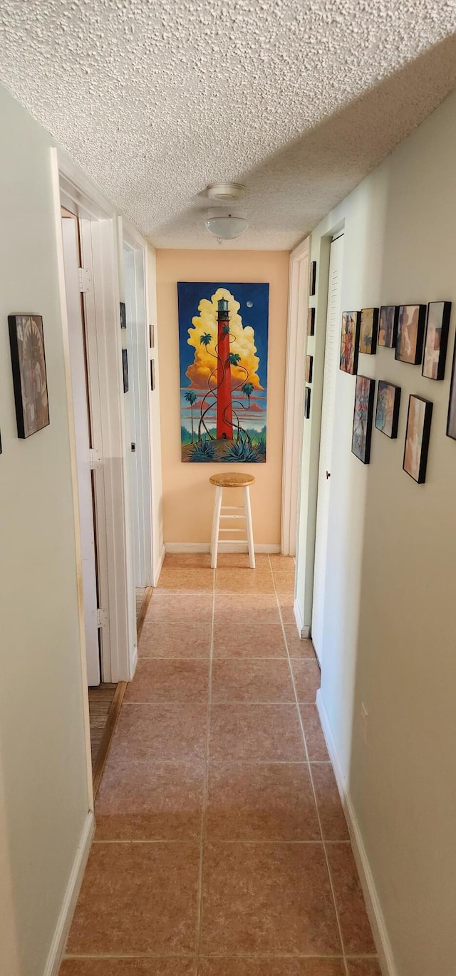 hall featuring tile patterned flooring and a textured ceiling