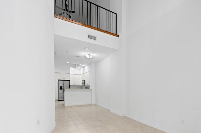 unfurnished living room with ceiling fan and a high ceiling