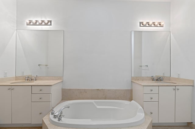 bathroom with vanity and tiled tub