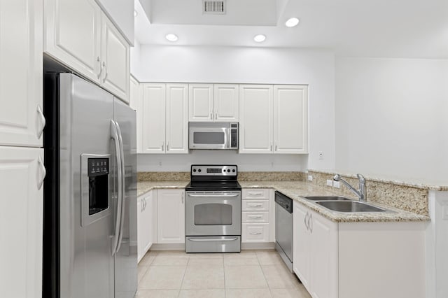 kitchen featuring appliances with stainless steel finishes, light stone counters, white cabinets, light tile patterned floors, and sink