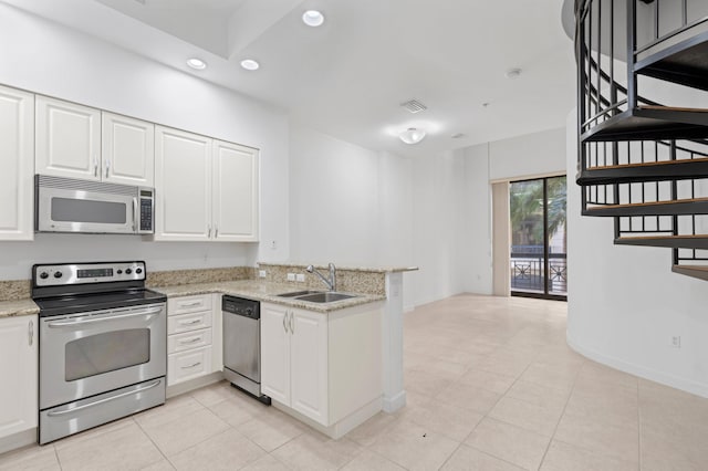 kitchen with appliances with stainless steel finishes, sink, light stone counters, white cabinetry, and kitchen peninsula