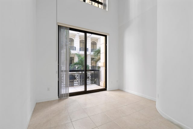 tiled empty room with a healthy amount of sunlight and a high ceiling