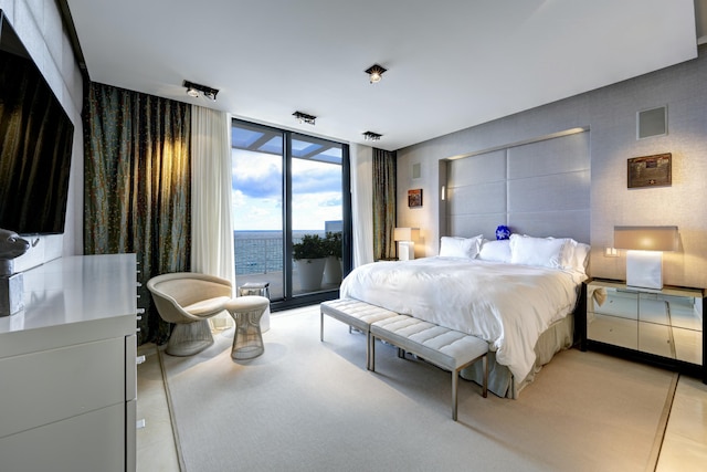 bedroom featuring access to exterior, floor to ceiling windows, and a water view