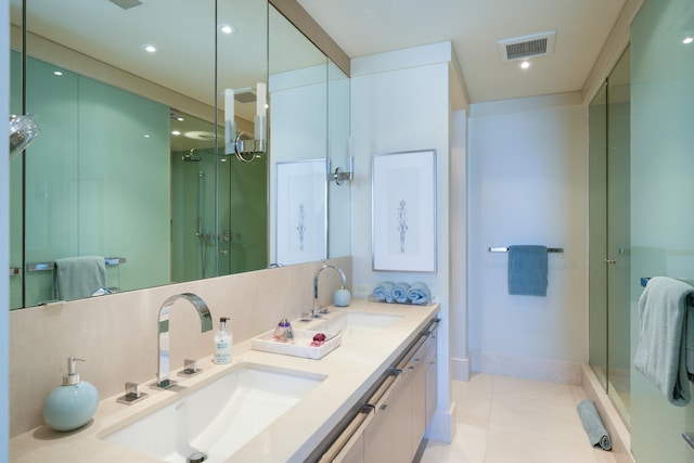 bathroom featuring dual vanity, a shower with door, and tile patterned flooring