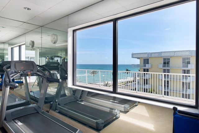 gym featuring a drop ceiling and a water view