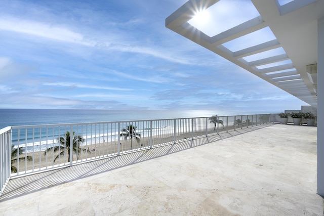 view of patio / terrace featuring a water view and a beach view