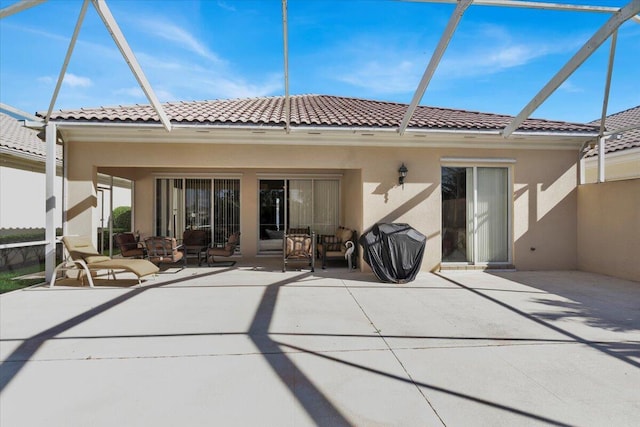 back of house featuring a lanai, a patio area, a tiled roof, and stucco siding