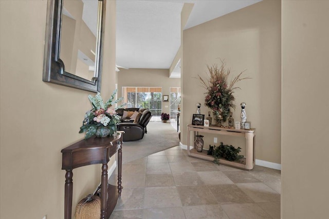 hall featuring baseboards and carpet flooring