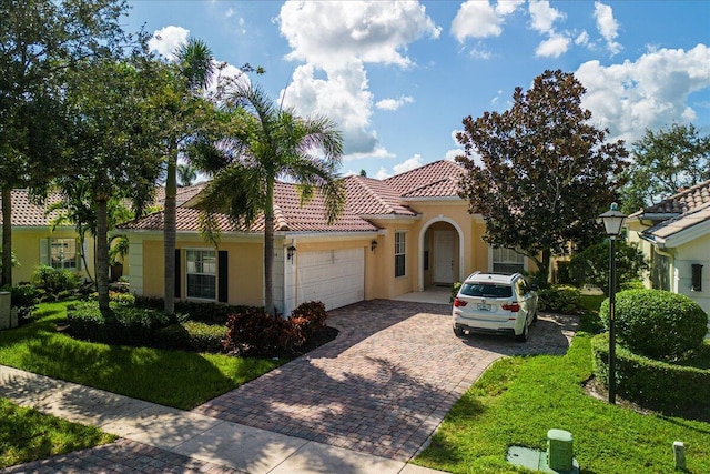 mediterranean / spanish-style home with a garage, decorative driveway, a tile roof, and stucco siding