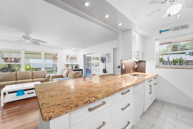 kitchen with white dishwasher, plenty of natural light, white cabinetry, and sink