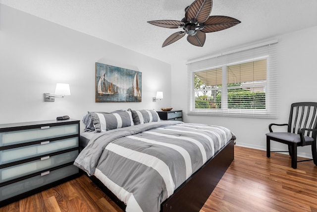 bedroom with ceiling fan, dark wood-type flooring, and a textured ceiling