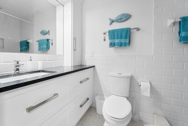 bathroom featuring tile patterned flooring, vanity, toilet, and tile walls