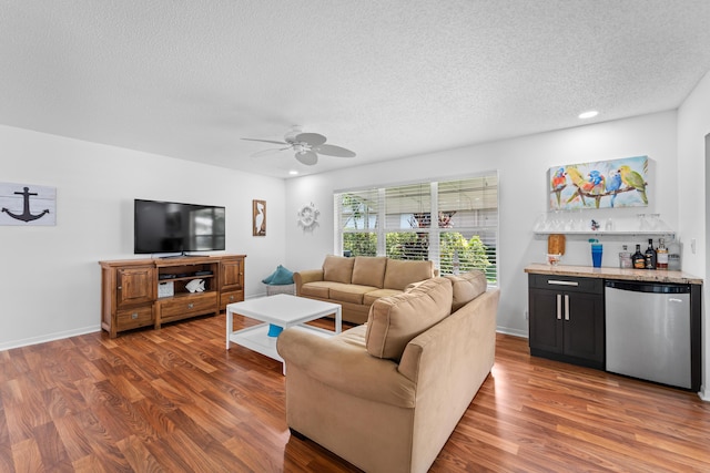 living room featuring a textured ceiling, ceiling fan, dark wood-type flooring, and bar area