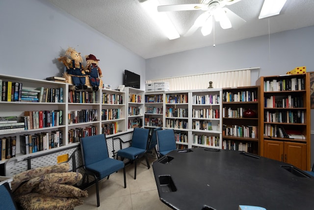 recreation room with ceiling fan, light tile patterned flooring, and a textured ceiling