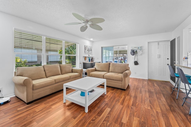 living room with a textured ceiling, ceiling fan, and dark hardwood / wood-style floors