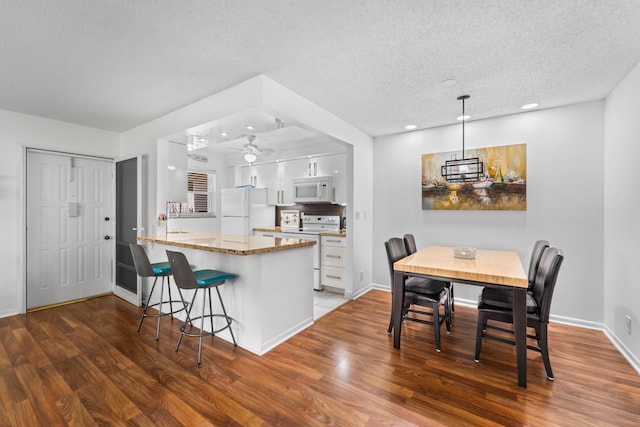 kitchen featuring kitchen peninsula, dark hardwood / wood-style flooring, white appliances, and white cabinets