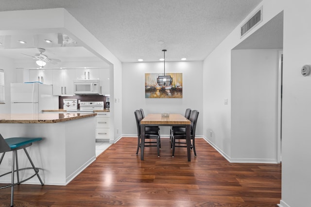 dining area featuring a textured ceiling, ceiling fan, and dark wood-type flooring